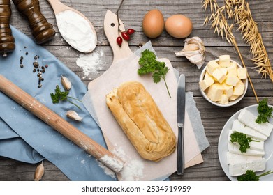 Cheese burek on Wooden Board with Rustic Cooking Ingredients. Puff Pastry and Fresh Ingredients Ready for Cooking, Rustic Style. Balkan national dish. - Powered by Shutterstock