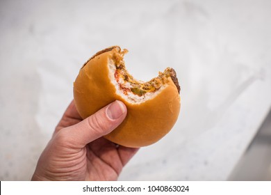 Cheese Burger In Hand With A Bite Taken Out Of It