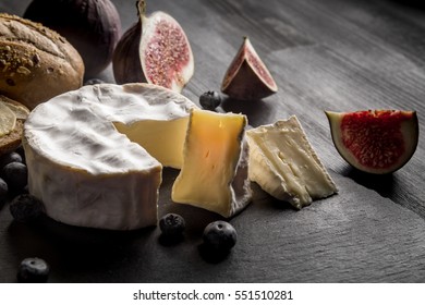 Cheese Camembert with figs and blackberries on old black wooden table. Food for wine and romantic, cheese and bread delicatessen.  Text area space.
