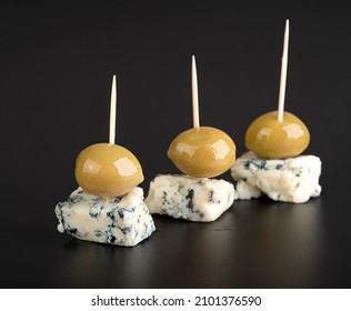 Cheese canapes with blue mold and large green olives on a black slate  - Powered by Shutterstock