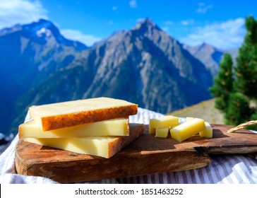 Cheese collection, French comte, beaufort or abondance cow milk cheese served outdoor with Alps mountains peaks in summer on background