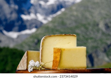 Cheese collection, French cow cheese comte, beaufort, abondance and snowy tops of french Aples mountains village in summer in Haute-Savoie on background