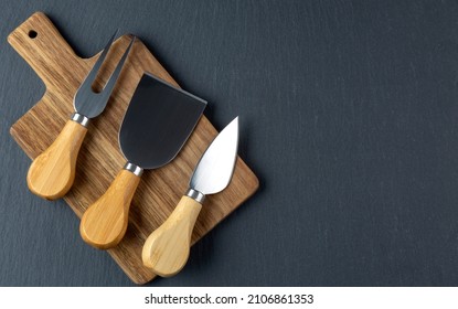 Cheese cutter set with wooden handles. Group of cheese knives on the cutting board. - Powered by Shutterstock