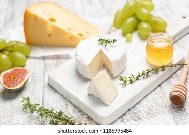 Cheese, grapes, honey and herbs on white board. Selective focus. Tasty cheese plate - Powered by Shutterstock