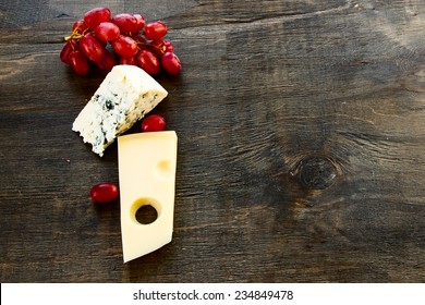 Cheese And Grapes On Rustic Wooden Background. Top View.