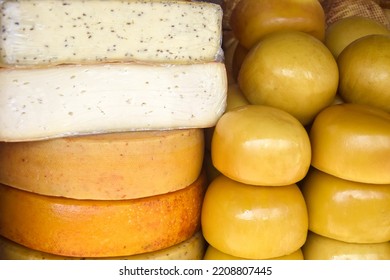 Cheese heads of different colors and sizes are stacked on counter. Fair trade in homemade cheese, market. Close-up. Selective focus. - Shutterstock ID 2208807445
