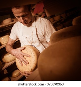 Cheese Maker Cleaning Cheeses In His Workshop