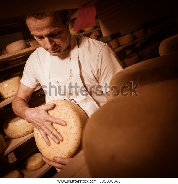 Cheese maker\
cleaning cheeses in his\
workshop