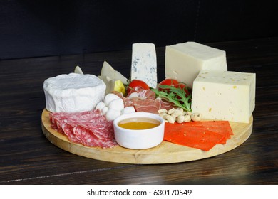 Cheese And Meat Platter With Tomatoes, Honey, Prosciutto On Wooden Board