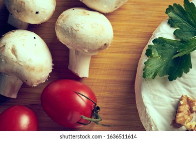 Cheese mushrooms and tomatoes on wooden deck.