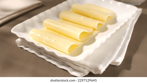 cheese on white plates. dairy products on a brown background. gouda cheese close-up. slices of yellow cheese. farm product - Powered by Shutterstock