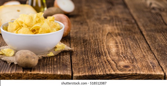 Cheese and Onion Potato Chips on an old wooden table as detailed close-up shot (selective focus)