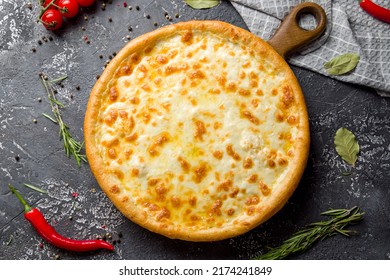Cheese pizza on board on dark stone table top view