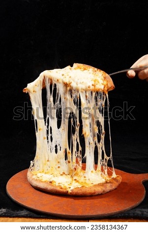 Cheese pizza on wooden table, dark interior background, period wooden furniture, retro style