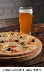 Cheese Pizza With Tomatoes And Olives On A Wooden Platter And A Glass Of Light Beer On The Table In The Pub. Vertical Orientation, Close-up, Copy Space, No People