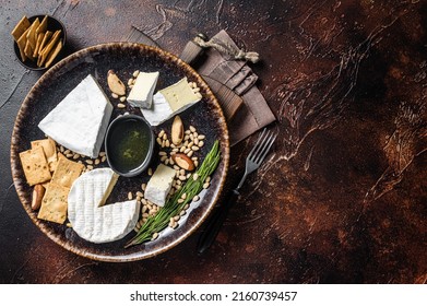 Cheese plate with brie and camembert on rustic plate with nuts and honey. Dark background. Top view. Copy space.