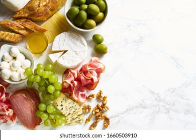 Cheese Plate With Brie, Parmesan, Cheddar And Meat. Flatlay With Variety Of Gourmet Snacks, Fruits And Baguette On Marble Board. Copy Space