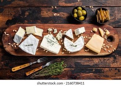 Cheese Plate With Camembert, Brie, Gorgonzola, Parmesan, Olives, Nuts And Crackers. Wooden Background. Top View.