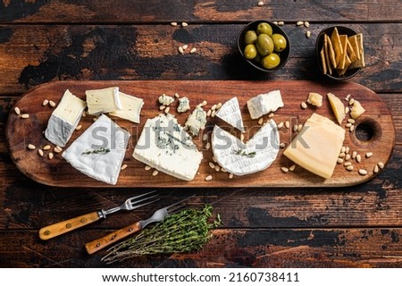Cheese plate with camembert, brie, Gorgonzola, parmesan, olives, nuts and crackers. Wooden background. Top view.