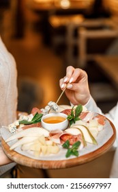 Cheese Plate With Honey In A Restaurant. Female Hands Dip Cheese Into Honey.