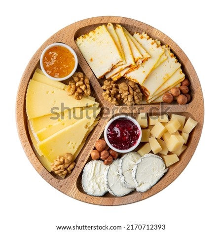 Cheese plate isolated on white background. Different cheese served with nuts and jam on wooden tray. Cheese platter. Top view.