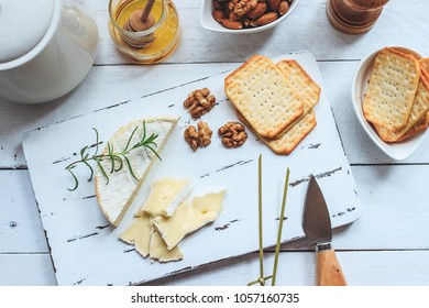 Cheese plate served with crackers, honey and nuts. Camembert on white wood serving board over white texture background. Appetizer theme. Top view - Powered by Shutterstock