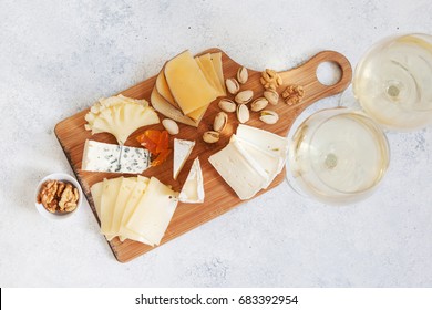 Cheese plate served with white wine, crackers and nuts, Top view. Assorted cheeses Camembert, Brie, Parmesan blue cheese, goat