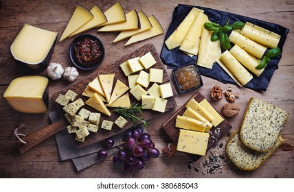 Cheese Plates Served With Grapes, Jam, Figs, Crackers And Nuts On A Wooden Background, Top View