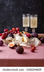 Cheese Platter. Brie Cheese On Parchment Paper With Fresh Ripe Figs, Plums And Grape. Champagne On Background 