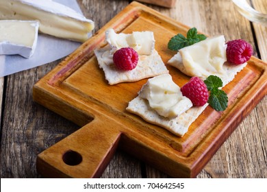 Cheese Platter. Brie Soft Cheese Served With Fresh Raspberries And Crackers On Rustic Wooden Cutting Board 