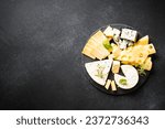 Cheese platter with craft cheese assortment at black background.