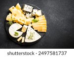 Cheese platter with craft cheese assortment at black background.