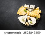 Cheese platter with craft cheese assortment at black background.