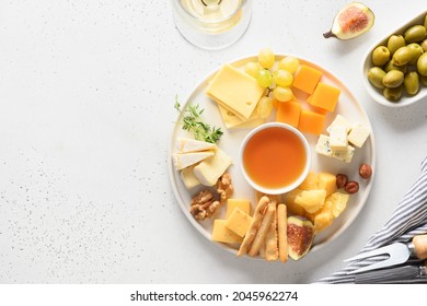 Cheese platter with different cheese and grapes, nuts, olive, figs on a white background with copy space. Top view. Festive gourmet appetizer.
