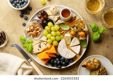 Cheese platter with fruits, nuts and snacks. Warm background. Top view. - Powered by Shutterstock