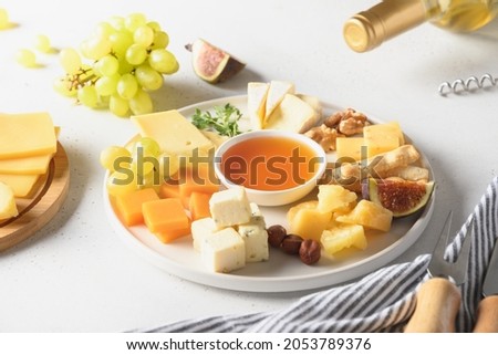 Cheese platter with fruits on a white background. Close up. Festive gourmet snack.