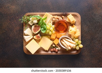 Cheese Platter With Grapes, Nuts, Figs On A Brown Background. Top View. Festive Gourmet Appetizer For Holiday.