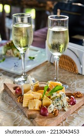 Cheese Platter With Honey, Walnuts And Grapes And Two Glasses Of Champagne On A Table In A Cafe