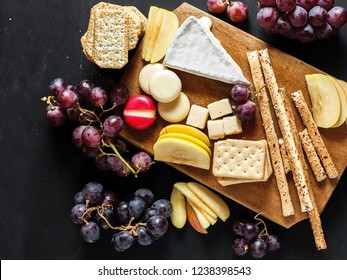 Cheese platter on cutting board with pieces of fresh apple and grains on a black chalkboard background - Powered by Shutterstock