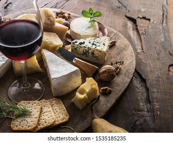 Cheese platter with organic cheeses, fruits, nuts and wine on wooden background. Tasty cheese starter. - Powered by Shutterstock