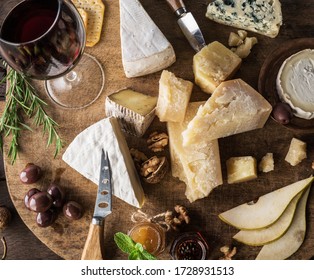 Cheese Platter With Organic Cheeses, Fruits, Nuts And Wine On Wooden Table. Top View. Tasty Cheese Starter.