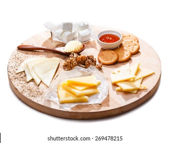 Cheese Platter. Variety Of Cheeses Accompanied By Walnuts,honey, Crackers And Butter Roll On A Round Wooden Plate.