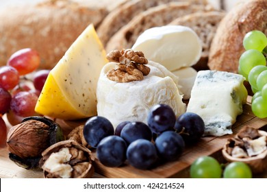 Cheese platter: variety of cheeses on wooden plate with fruits and bread - Powered by Shutterstock