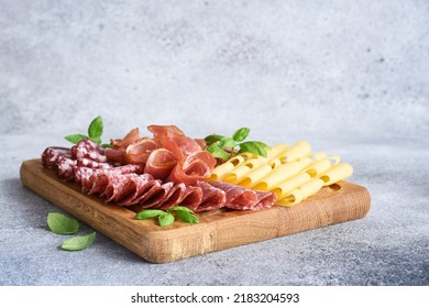 Cheese, prosciutto, salami on a wooden square board. Delicacy.
