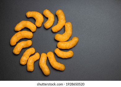 Cheese puffs flat lay, Cheese Doodle Day, symbol of the sun made of crisps, puffcorn