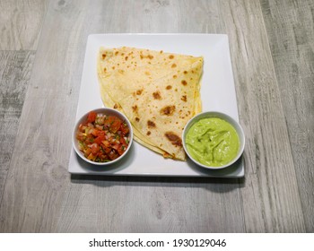 A Cheese Quesadilla With Pico De Gallo And Creamy Guacamole Served On A White Plate.