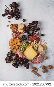 Cheese, slicing salami, ham, grapes, nuts and fruits on marble board. Party snacks.  Wine snacks on white background, top view 