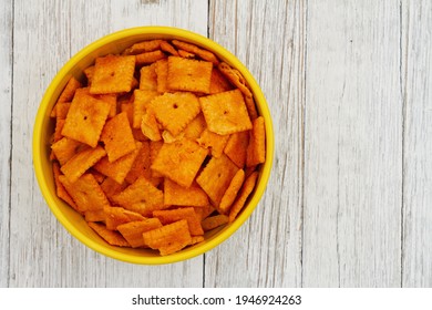 Cheese square crackers in bowl on weathered whitewashed wood table