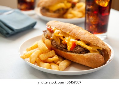 cheese steak sandwich accompanied by fries and an ice cold cola