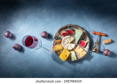 Cheese And Wine Tasting, Overhead Flat Lay Shot On A Blue Background With A Place For Text. Brie, Blue Cheese And Other Cheeses, With A Glass Of Red Wine